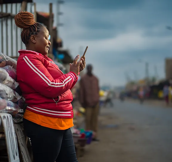 Woman in red jacket using a smartphone on a busy street.