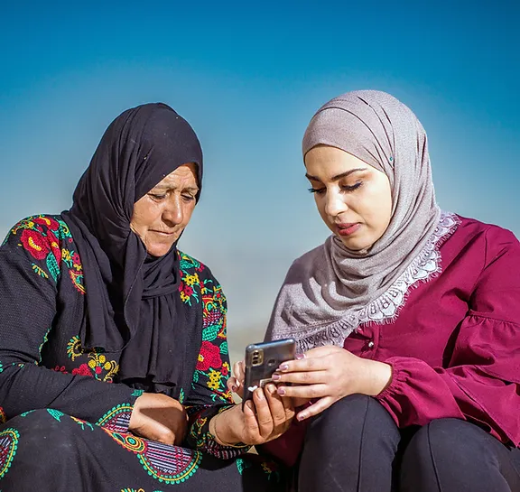 FINCA employee conducting a survey on a smartphone with another women.