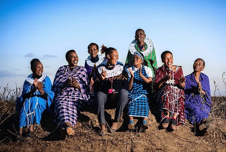 Group of women in traditional clothing sitting and clapping.