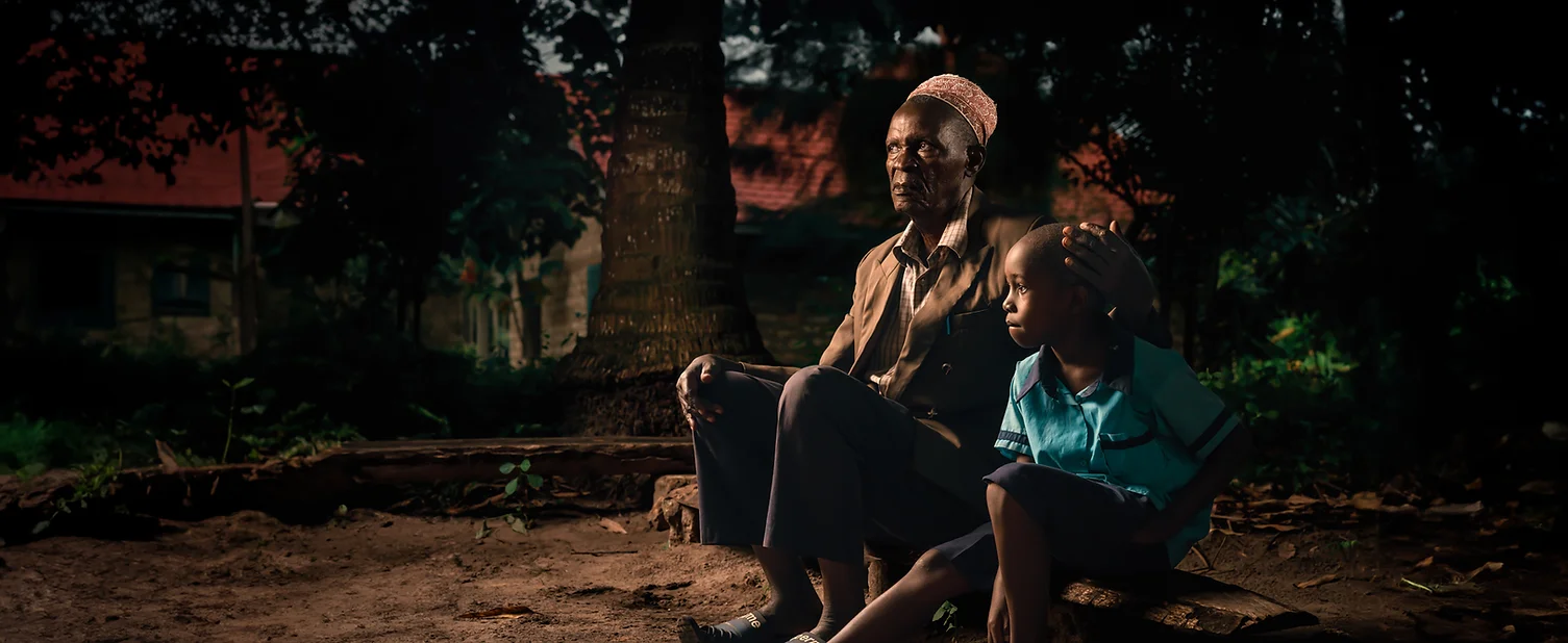 Elderly man and young boy sitting together outdoors.