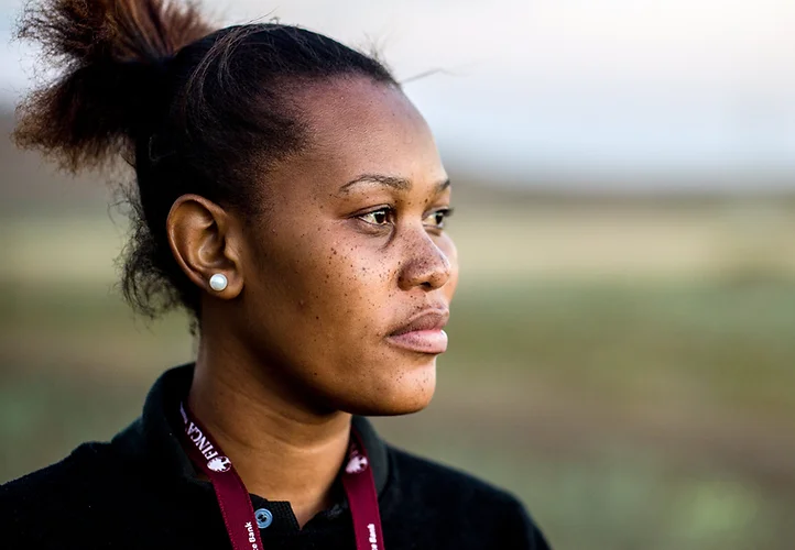 Woman looking into the distance, wearing a black shirt and FINCA lanyard.